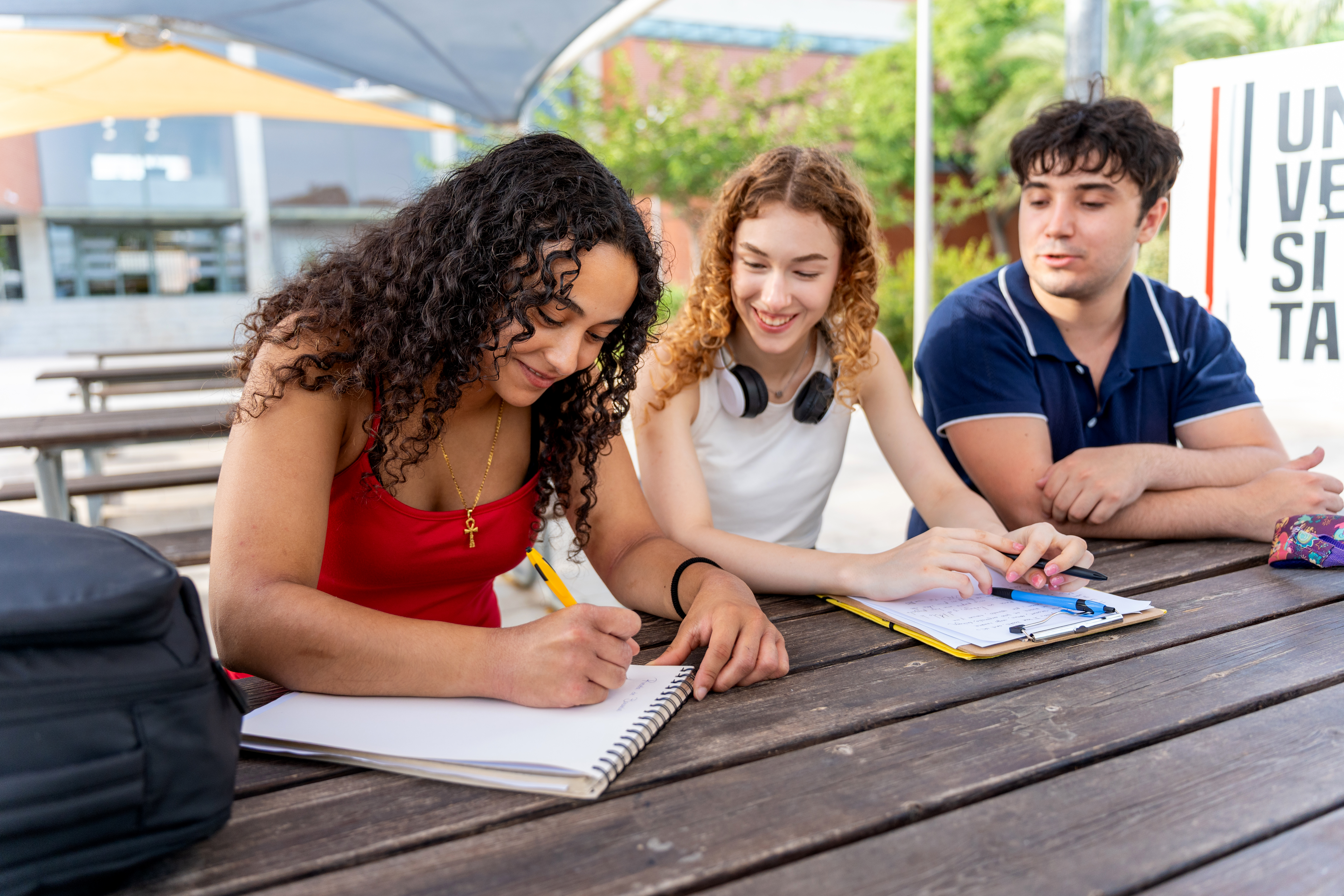 Diverse college students working together at a picnic table, preparing for final exams